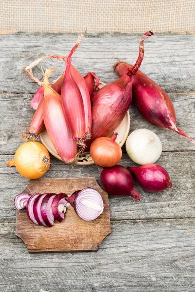 Verschiedene Zwiebelsorten auf einer hölzernen Oberfläche — Stockfoto