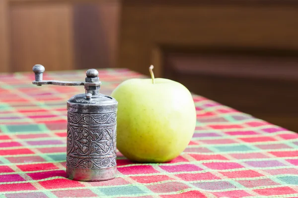 Still life composition with metallic pepper grinder and green apple — Stock Photo, Image