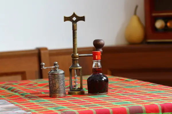 Still life sammansättning med metalliskt peppar kvarn, liten flaska aromatiska vinäger och koppar korkskruv på träbord — Stockfoto