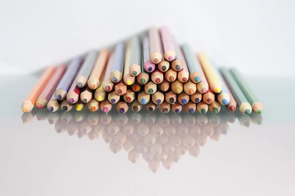 Sekelompok pensil berwarna tajam dengan latar belakang putih dan refleksi — Stok Foto