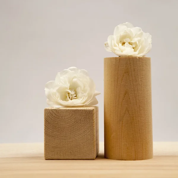 Piezas geométricas de madera con rosas blancas y fondo gris claro —  Fotos de Stock