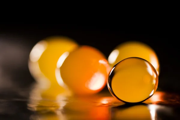 Abstract composition with beautiful, orange, round jelly balls on an aluminium foil with reflexions and dark background — Stock Photo, Image