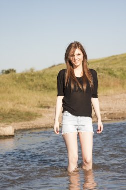 poz ve küçük bir nehir su ile oynarken düz saçlı güzel kız