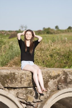 poz ve beton köprü üzerinde küçük bir nehir üzerinde oynama düz saçlı güzel kız