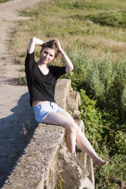 poz ve beton köprü üzerinde küçük bir nehir üzerinde oynama düz saçlı güzel kız