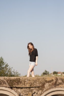 poz ve beton köprü üzerinde küçük bir nehir üzerinde oynama düz saçlı güzel kız