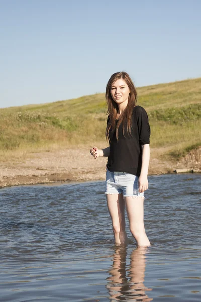 Belle fille aux cheveux longs et raides posant et jouant avec l'eau dans une petite rivière — Photo