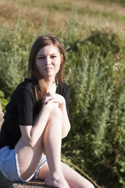 Bella ragazza con lunghi capelli dritti in posa e giocare su un ponte di cemento su un piccolo fiume — Foto Stock