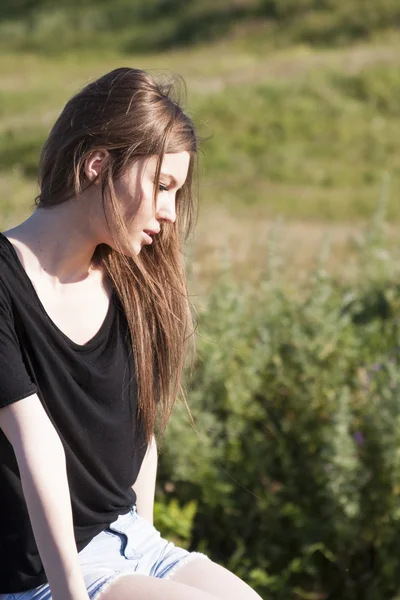 Beautiful girl with long, straight hair posing in the field looking melancholic — Stock Photo, Image