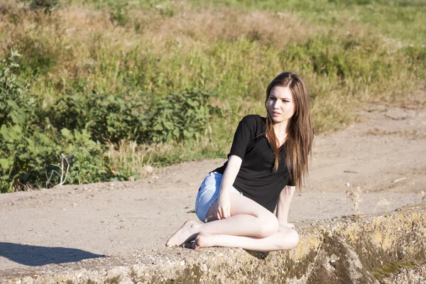 Hermosa chica con el pelo largo y liso posando y jugando en un puente de hormigón sobre un pequeño río — Foto de Stock