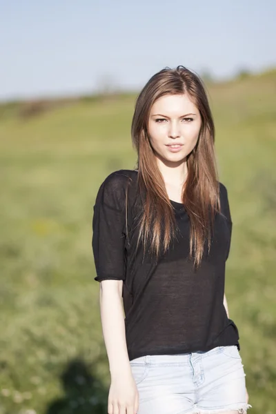 Schönes Mädchen mit langen, glatten Haaren posiert auf dem Feld und sieht melancholisch aus — Stockfoto