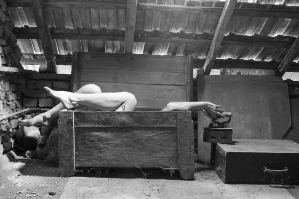 Black and white photo of woman in an wooden scuplted box in the attic with beautiful, moody light — Stock Photo, Image