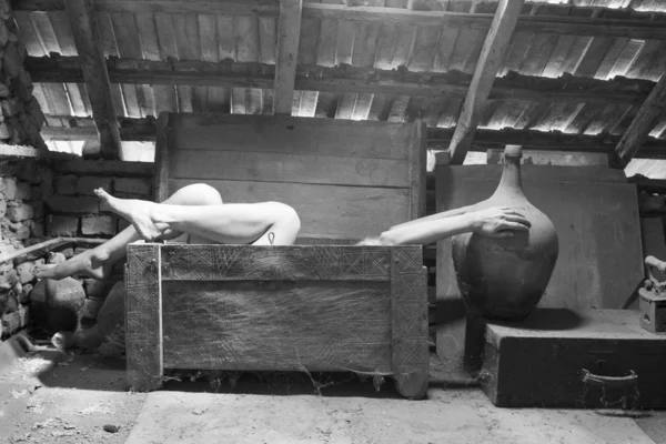 Foto em preto e branco de mulher em uma caixa de madeira no sótão com luz bonita e temperamental — Fotografia de Stock