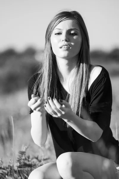Fotografie alb-negru a unei fete frumoase cu păr lung și drept care prezintă în câmp în căutarea melancolică — Fotografie, imagine de stoc