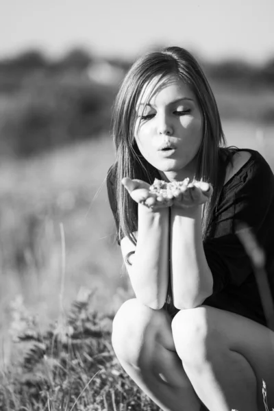 Black and white photo of beautiful girl with long, straight hair posing in the field looking melancholic — Stock Photo, Image