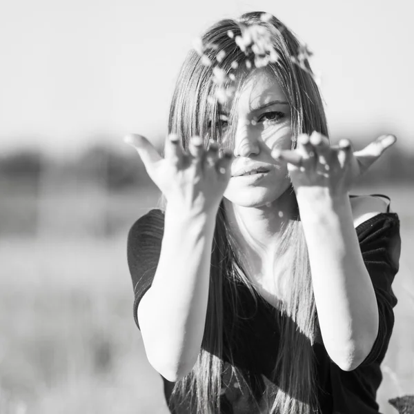 Черно-белое фото красивой девушки с длинными прямыми волосами, позирующими в поле и выглядящими меланхоличными — стоковое фото
