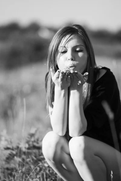 Black and white photo of beautiful girl with long, straight hair posing in the field looking melancholic — Stock Photo, Image