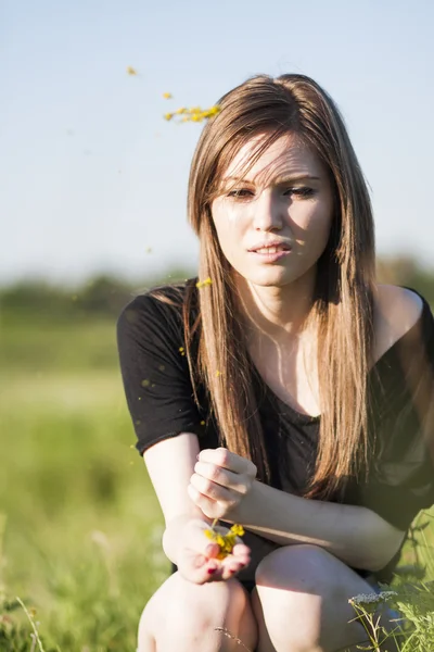 Beautiful girl with long, straight hair posing in the field looking melancholic — Stock Photo, Image
