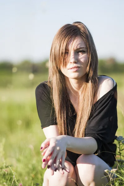 Hermosa chica con el pelo largo y liso posando en el campo buscando melancólico — Foto de Stock