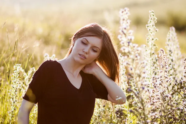 Beautiful girl with long, straight hair posing in the field looking melancholic — Stock Photo, Image