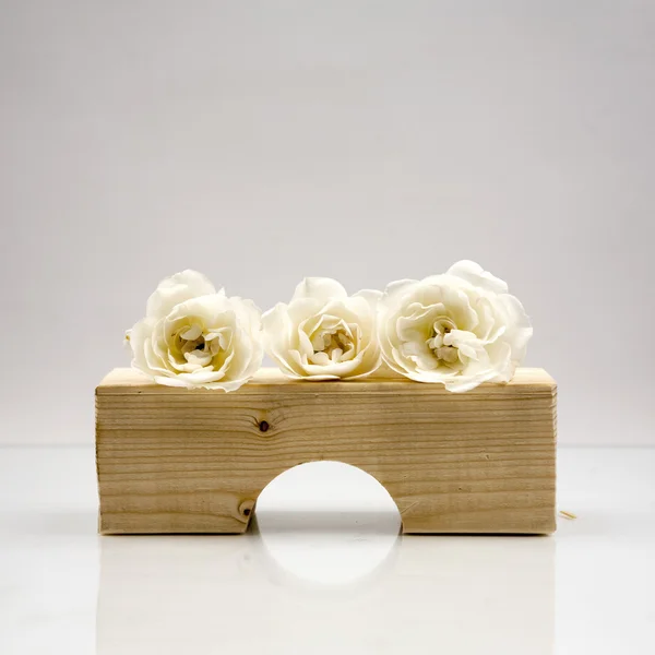 Pièces géométriques en bois avec roses blanches et fond gris clair — Photo