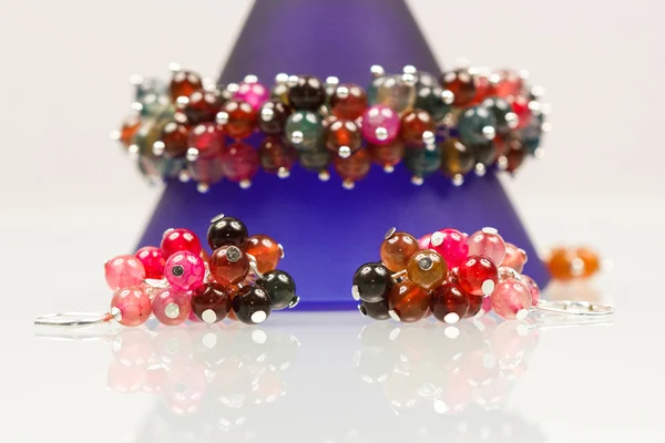 Ασημένια κοσμήματα με πολύχρωμες πολύτιμων λίθων και ανοιχτό γκρι φόντο — Φωτογραφία Αρχείου