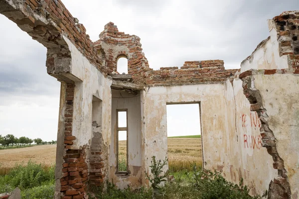 Partes de uma casa arruinada com céu dramático texturas e ervas diferentes — Fotografia de Stock