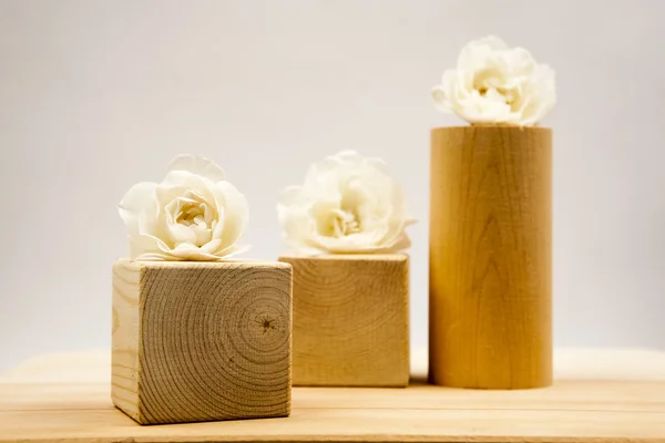 Wooden geometrical pieces with white roses and light grey background — Stock Photo, Image