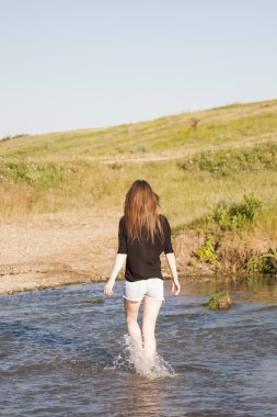 poz ve küçük bir nehir su ile oynarken düz saçlı güzel kız