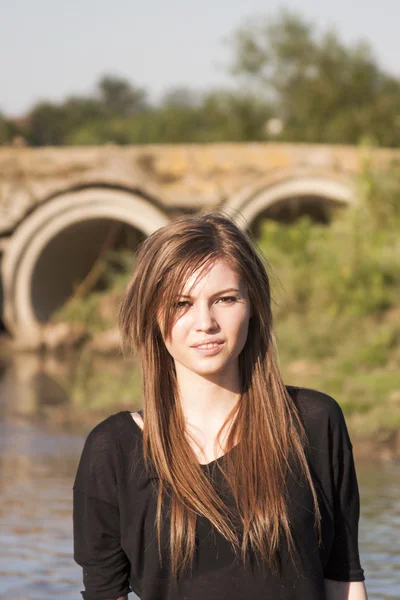 Bella ragazza con lunghi capelli dritti in posa e giocare con l'acqua in un piccolo fiume — Foto Stock