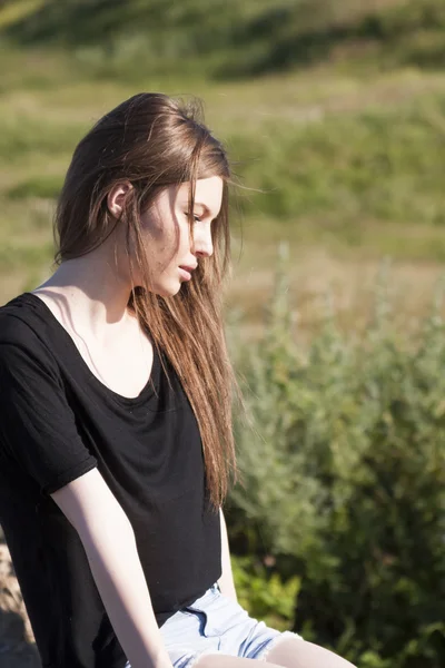 Beautiful girl with long, straight hair posing in the field looking melancholic — Stock Photo, Image