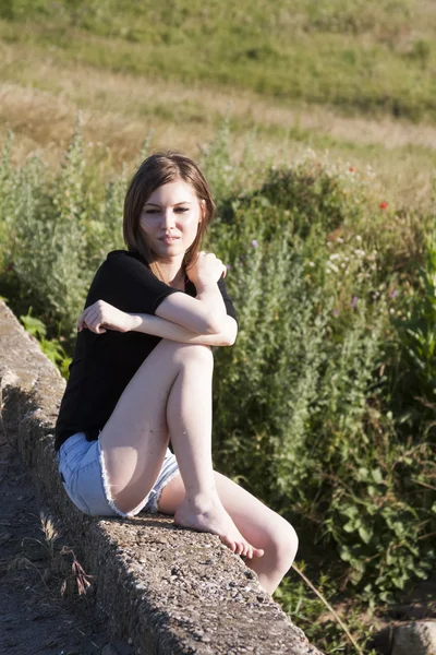 Hermosa chica con el pelo largo y liso posando en el campo buscando melancólico — Foto de Stock