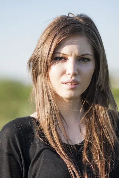 Beautiful girl with long, straight hair posing in the field looking melancholic — Stock Photo, Image