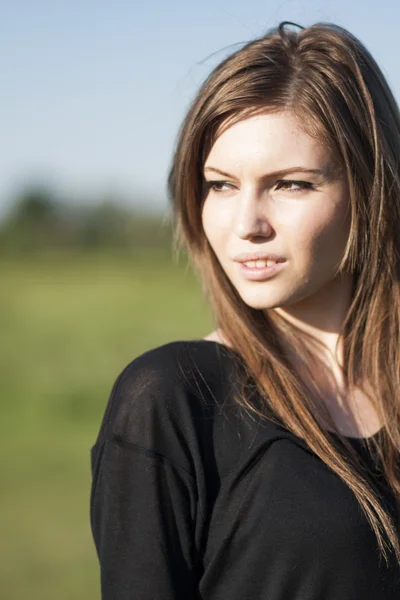 Hermosa chica con el pelo largo y liso posando en el campo buscando melancólico — Foto de Stock