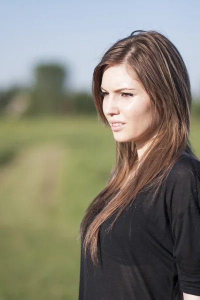 Beautiful girl with long, straight hair posing in the field looking melancholic — Stock Photo, Image