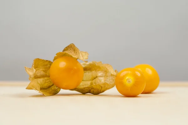 Pendekatan buah Physalis peruviana dengan latar belakang abu-abu muda dan refleksi — Stok Foto