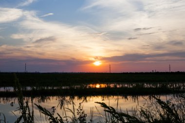 Güzel, dramatik, renkli bulutlar ve gökyüzü gün batımında. Elektrik telleri ve kazık ve su yenilgileri