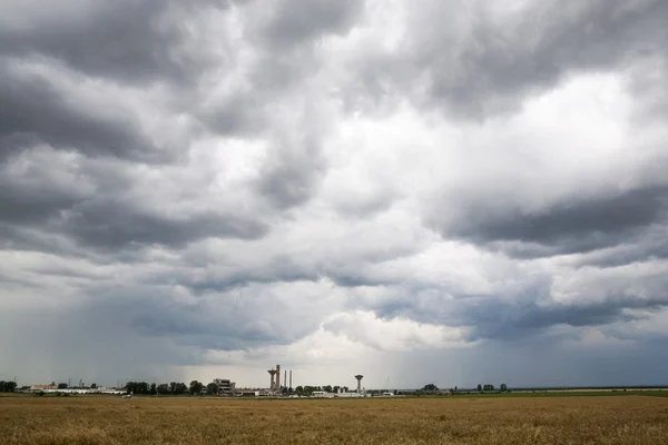 Industrial landscape with wheat field and dramatic clouds — Stock Photo, Image