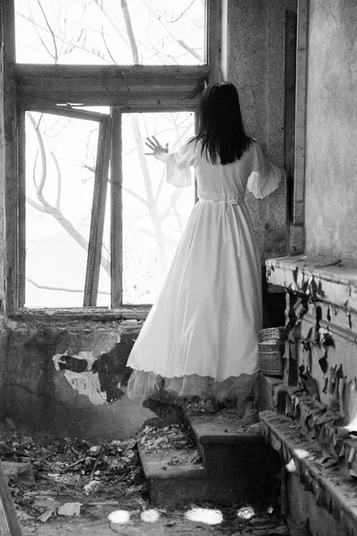 Starea de spirit tristă într-o casă veche, abandonată, cu o fată care poartă o rochie de mireasă de modă veche cu lumină naturală. Fotografia are textura cerealelor vizibilă pe dimensiunea maximă. Fotografie artistică alb-negru — Fotografie, imagine de stoc