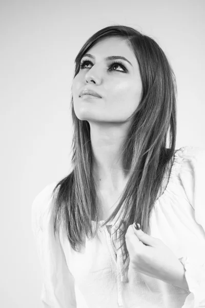 Foto en blanco y negro de una hermosa chica caucásica con una blusa blanca con fondo gris claro — Foto de Stock