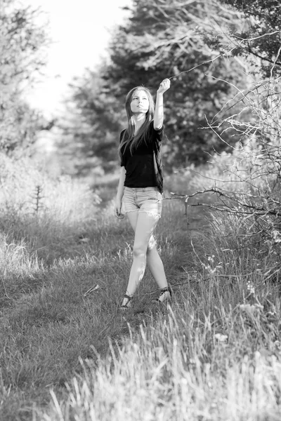 Beautiful girl with long, straight hair posing and playing with water in a small river. Black and white, artistic photography — Stock Photo, Image