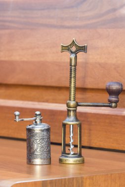 Metalik karabiber değirmeni ve ahşap masa üzerinde bakır tirbuşon ile natürmort kompozisyon