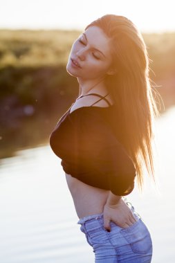 Işığa karşı günbatımı ışık alanıyla poz uzun, düz saçlı güzel kız