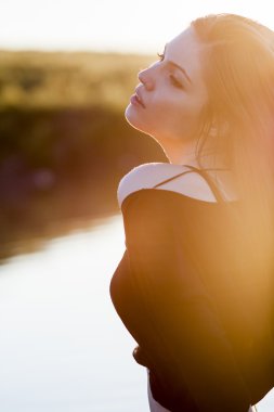 Işığa karşı günbatımı ışık alanıyla poz uzun, düz saçlı güzel kız