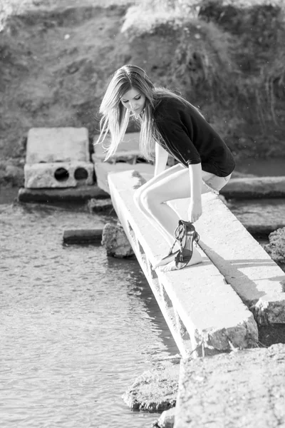 Belle fille aux cheveux longs et raides posant et jouant avec l'eau dans une petite rivière — Photo