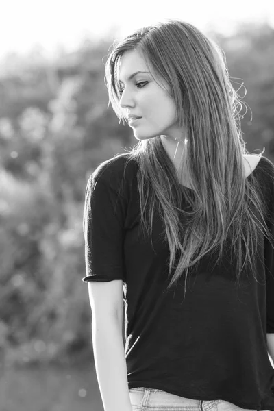 Hermosa chica de pelo largo y liso posando en el campo con luz del atardecer, contra la luz — Foto de Stock