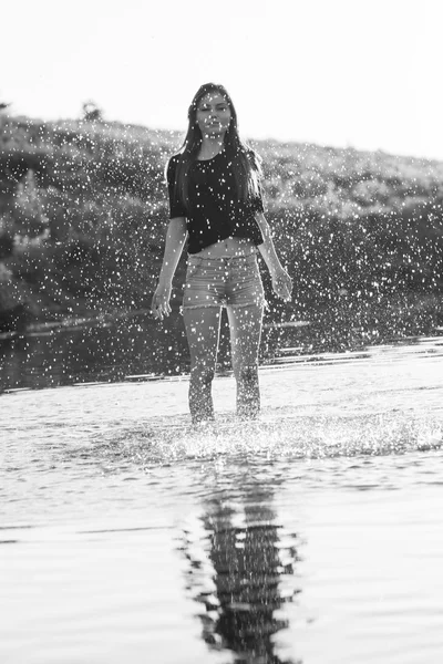 Beautiful girl with long, straight hair posing and playing with water in a small river — Stock Photo, Image
