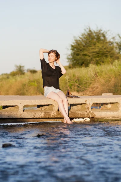 poz ve küçük bir nehir su ile oynarken düz saçlı güzel kız