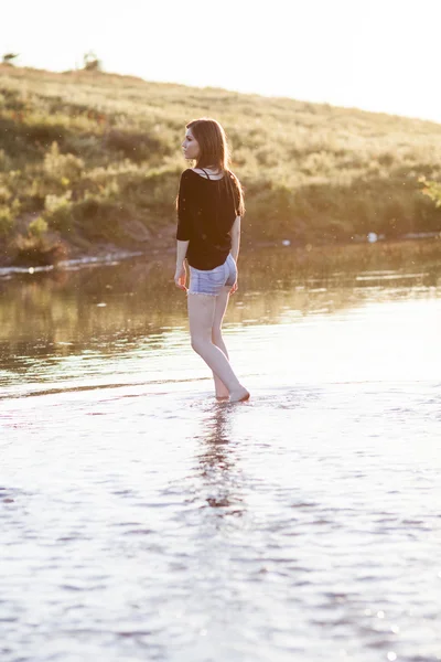 Işığa karşı günbatımı ışık alanıyla poz uzun, düz saçlı güzel kız