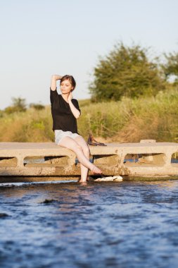 poz ve küçük bir nehir su ile oynarken düz saçlı güzel kız